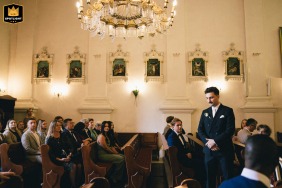 Poland, inside a historic church, is where the waiting groom stands solemnly at the altar, anticipating the arrival of his bride for their wedding ceremony.